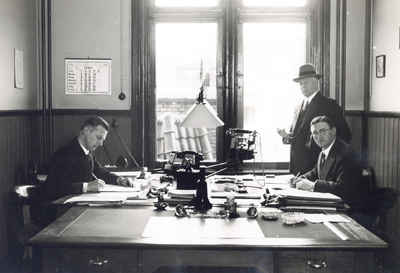 881938 Afbeelding van een kamer van het Inspectiebureau N.S. te Utrecht (?), met links dhr. Koolen en staande rechts ...